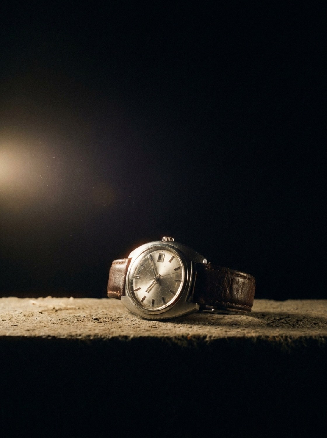Lichtserie: Armbanduhr auf rohem Beton im harten Seitenlicht